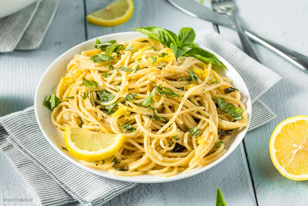 Lemon pasta on a white plate, garnished with fresh basil.