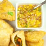 Overhead shot of raw mango chutney with samosas on the side.