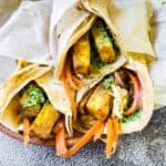 3 paneer rolls wrapped in parchment paper.