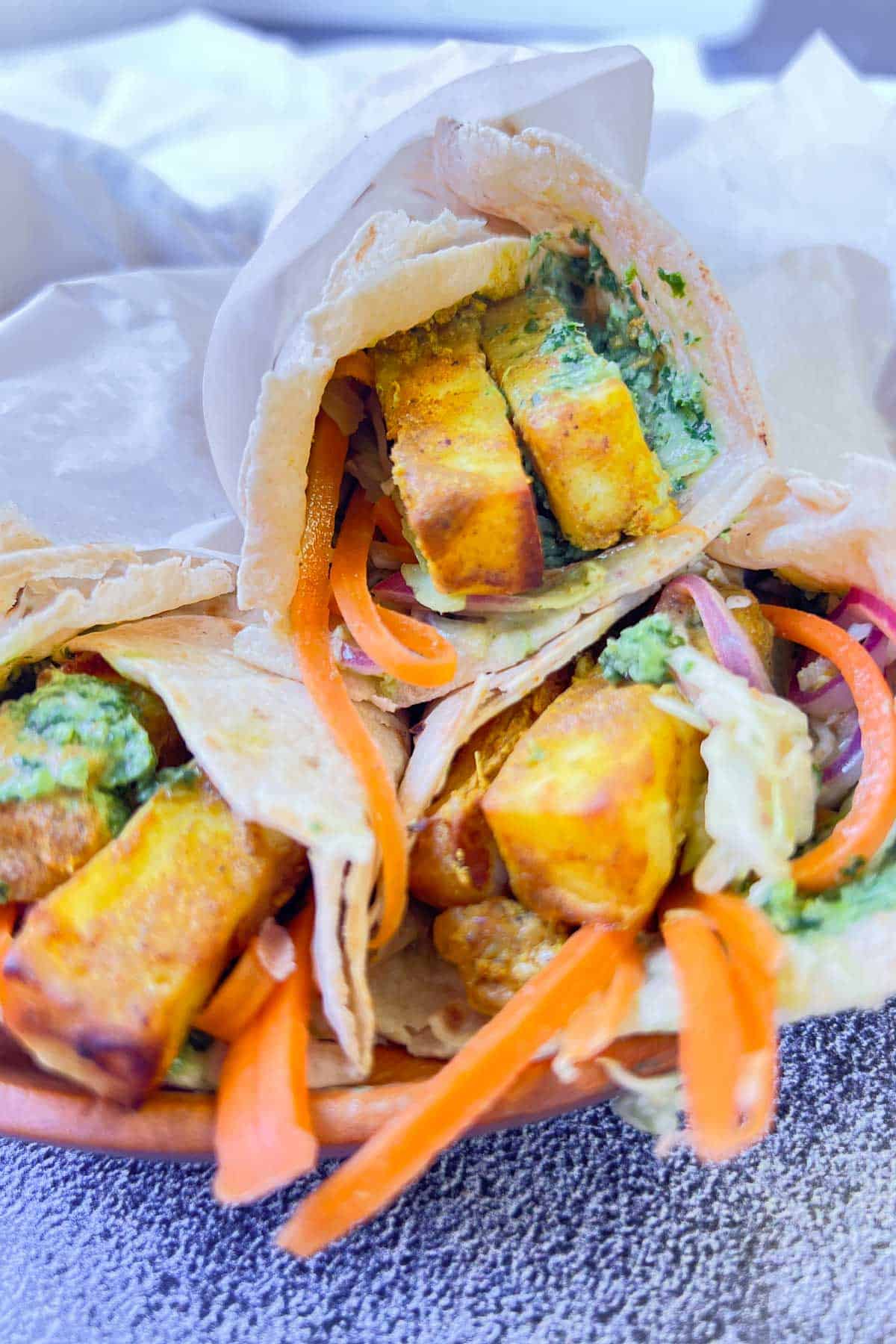 3 paneer rolls wrapped in parchment.