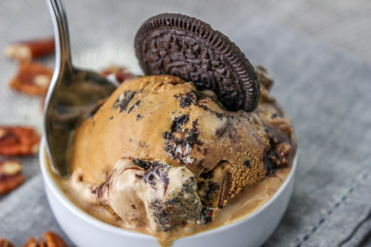 Low angle shot of a bowl of mississippi mud ice cream with an oreo cookie and a spoon stuck in it.