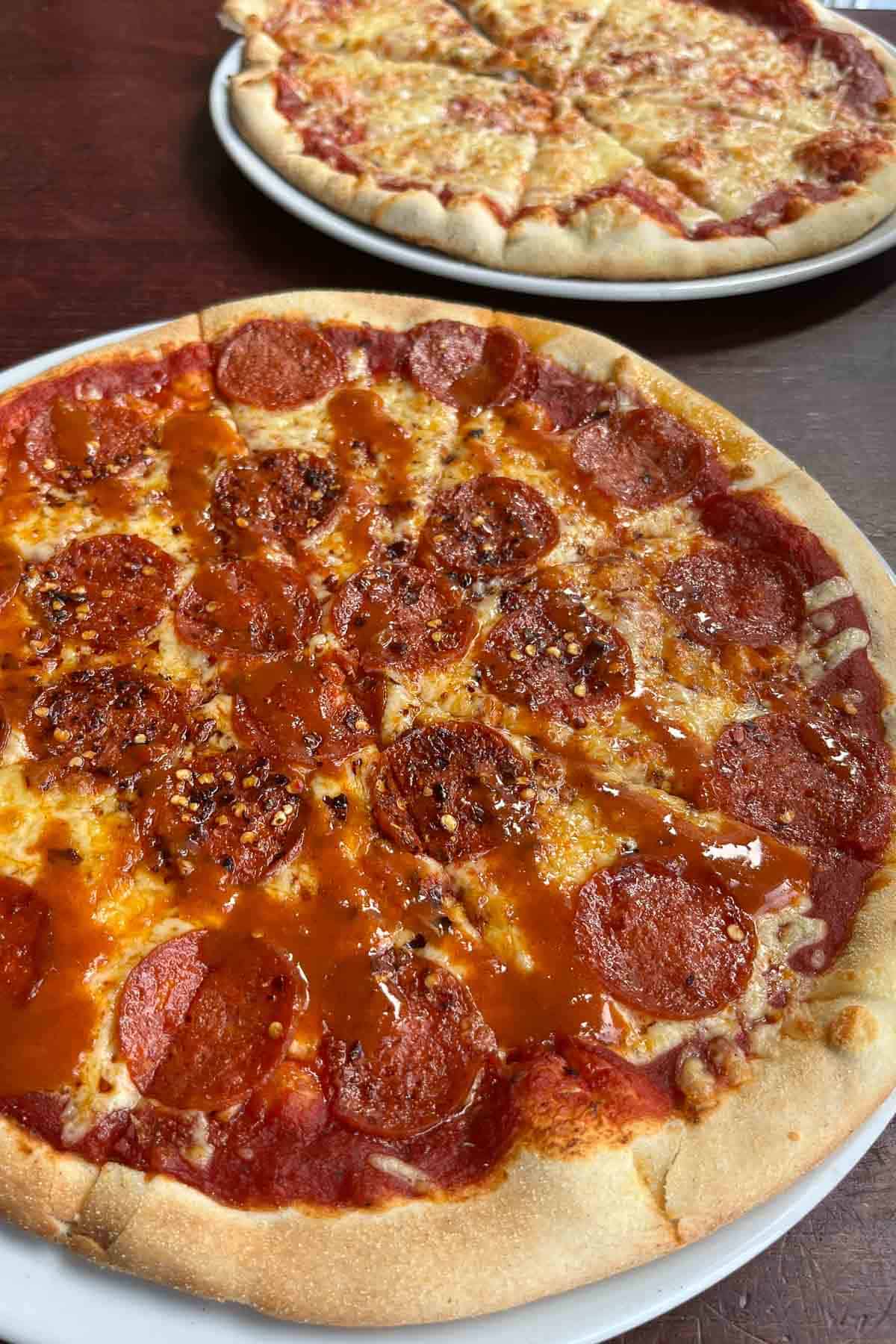 pepperoni pizza with a plain cheese pizza in the background.