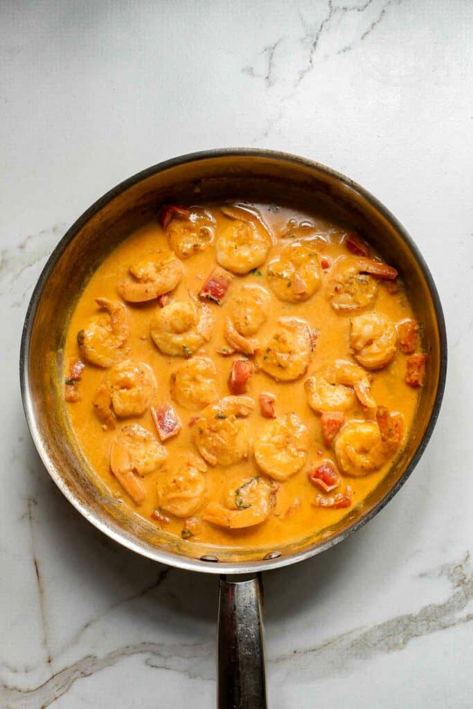 Thai shrimp curry with coconute milk simmering in a skillet.