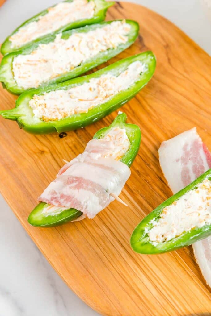 Stuffed jalapenos on a wooden cutting board.