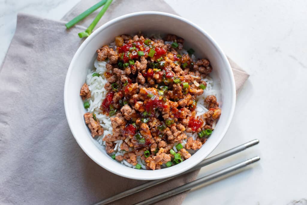 A white bowl with hoisin beef and rice.