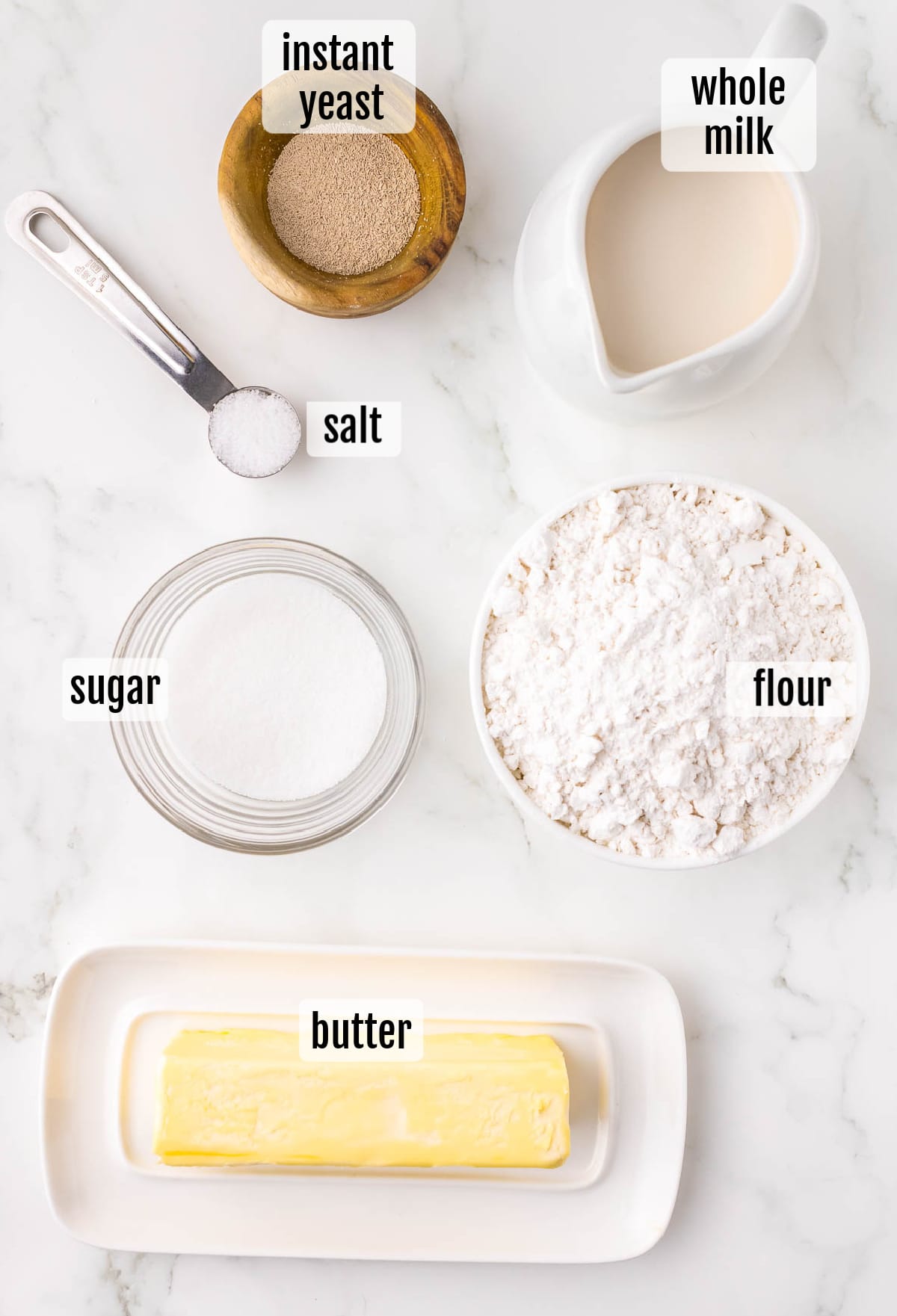 The ingredients for a recipe for buttermilk pancakes are shown on a white marble table.