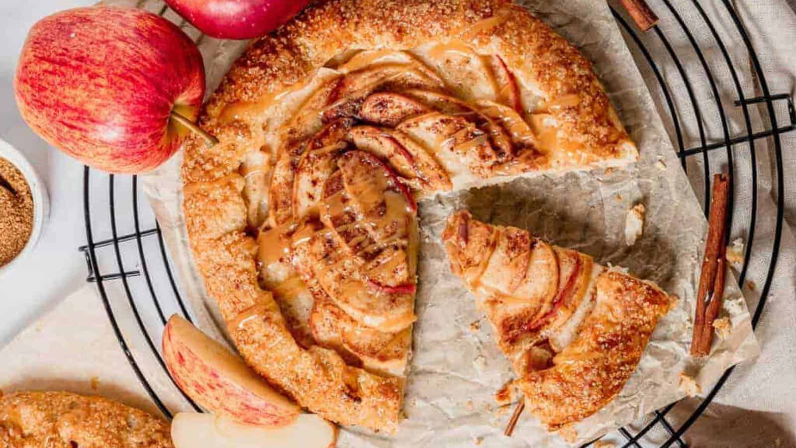 Overhead shot of an apple galette on parchment with fresh apples on the side.