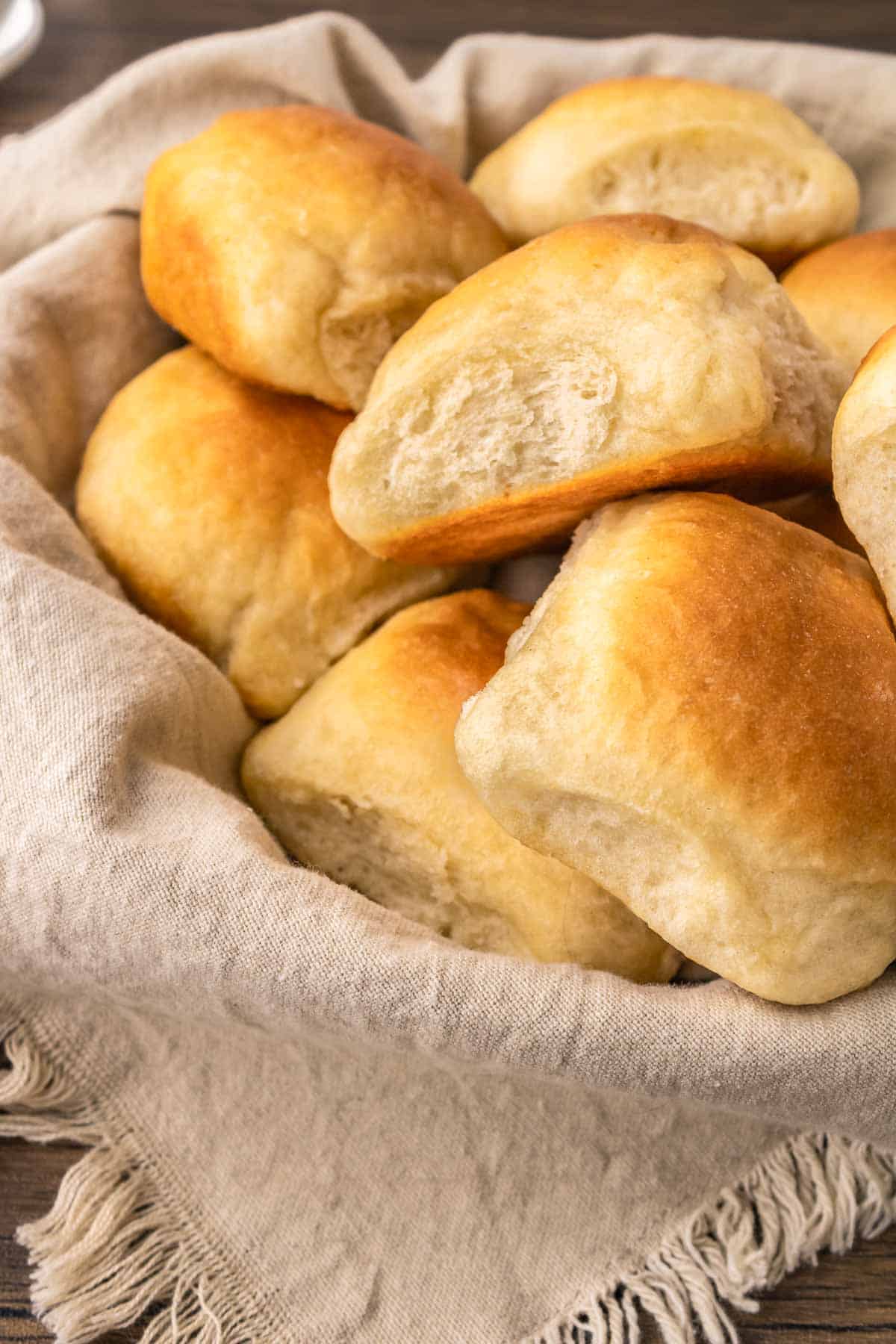 Bread rolls in a basket on a wooden table.