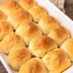 Bread rolls in a baking dish on a wooden table.