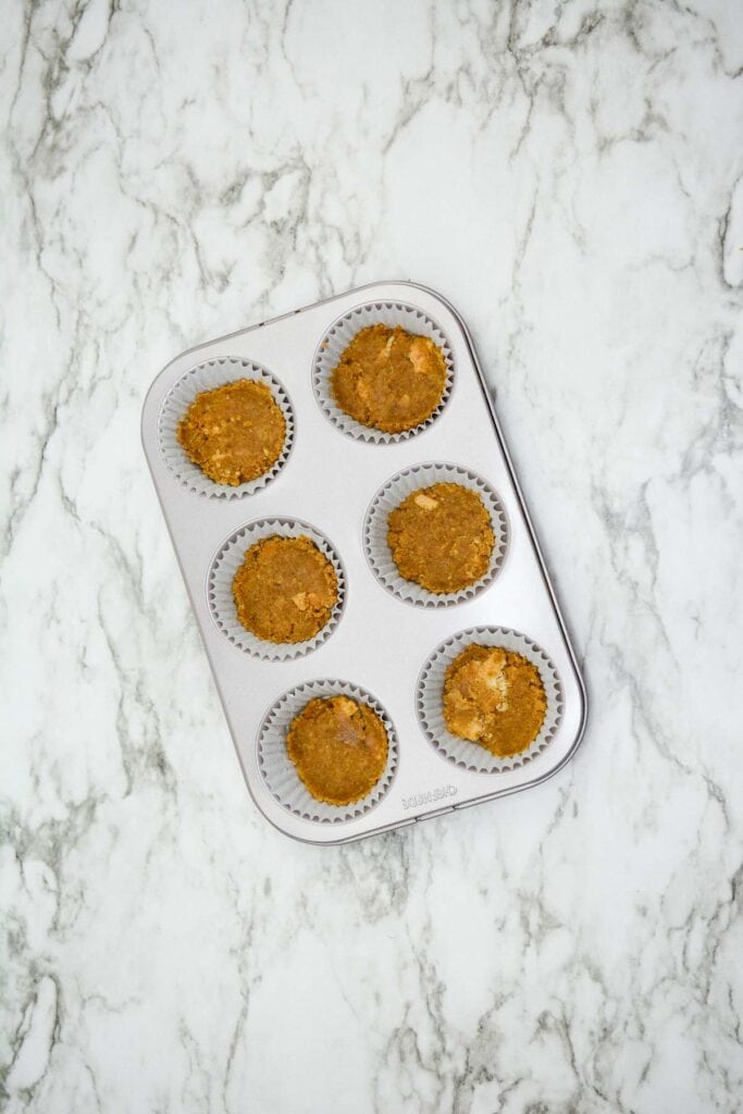 Mini pumpkin muffins in a muffin tin on a marble countertop.