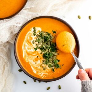 Curry pumpkin soup in a bowl with a spoon.