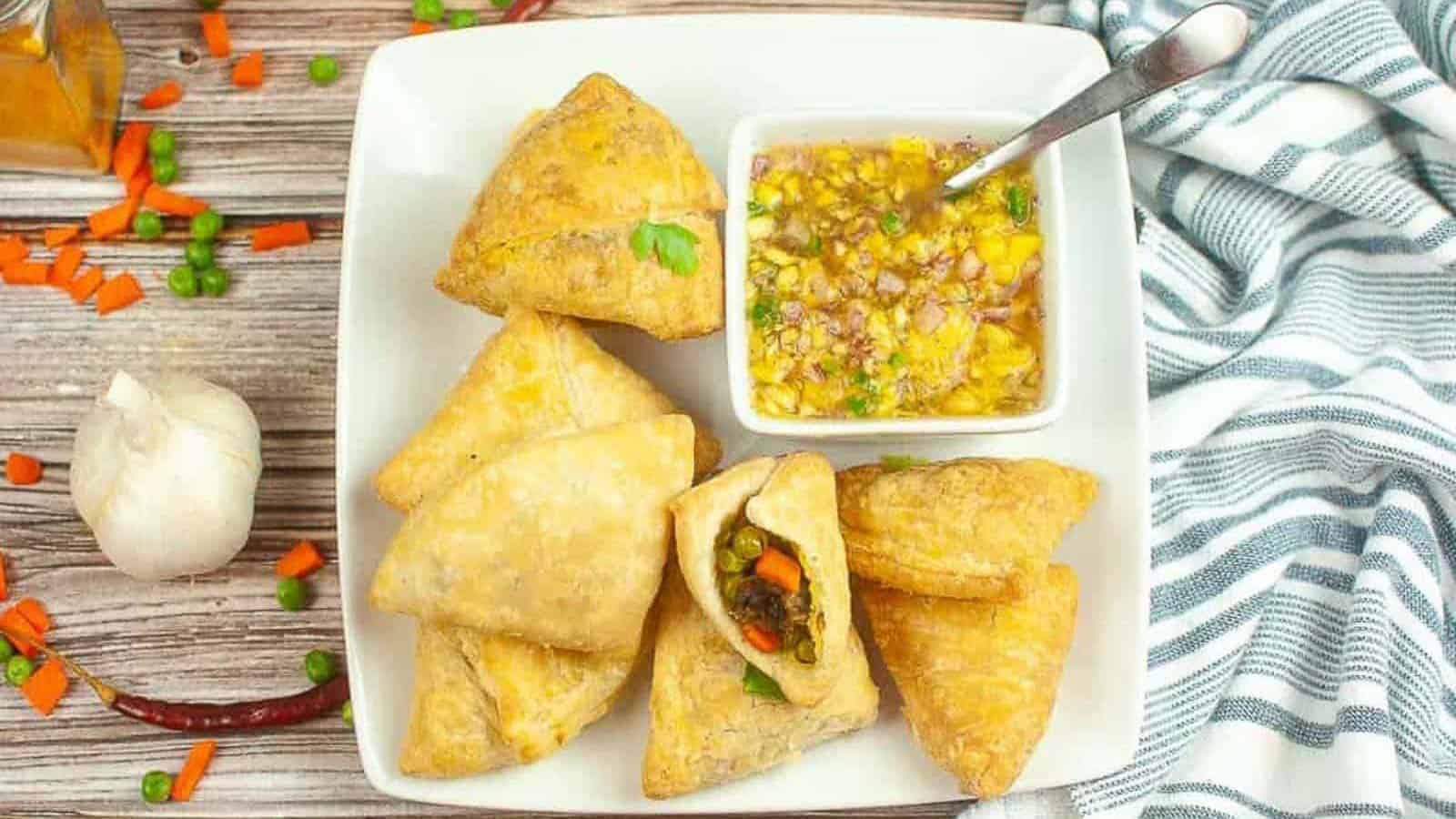 Overhead shot of a plate of samosas with raw mango chutney on the side for dipping.