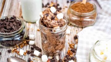 A jar of Rocky Road Ice Cream on a table with ingredients scattered around.