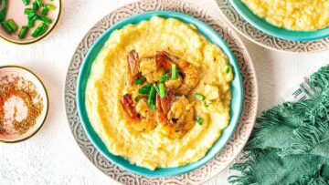A bowl of grits topped with cajun shrimp.