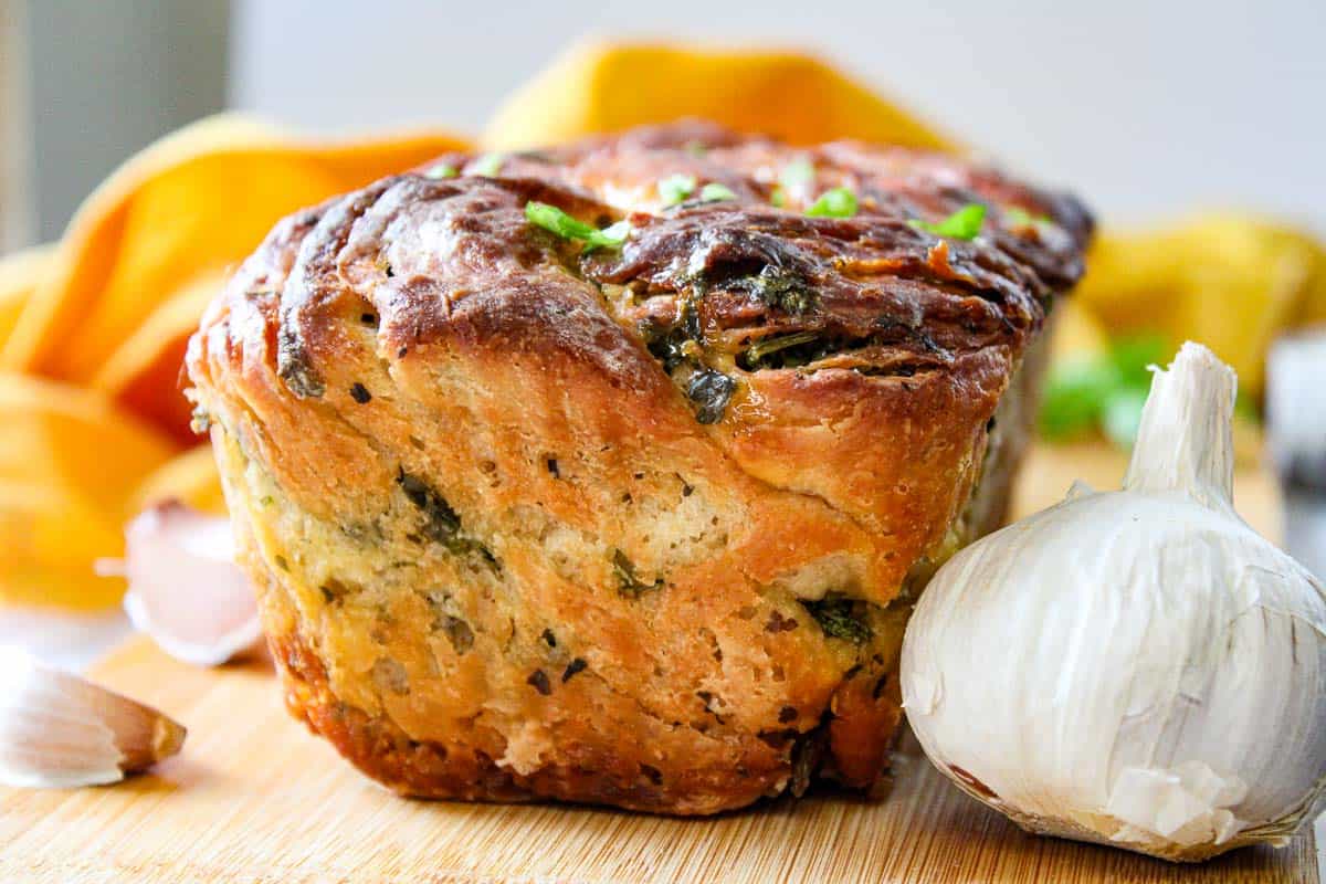 A loaf of bread with garlic and herbs on a cutting board.