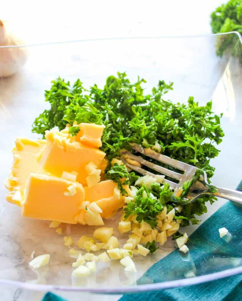 Shredded cheese and kale in a glass bowl with a fork.