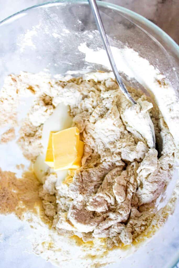 A bowl of ingredients with a spoon and a butter.