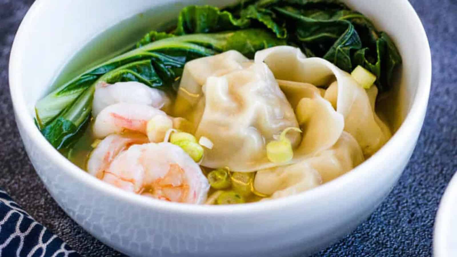 A bowl of wonton soup with shrimp in it.
