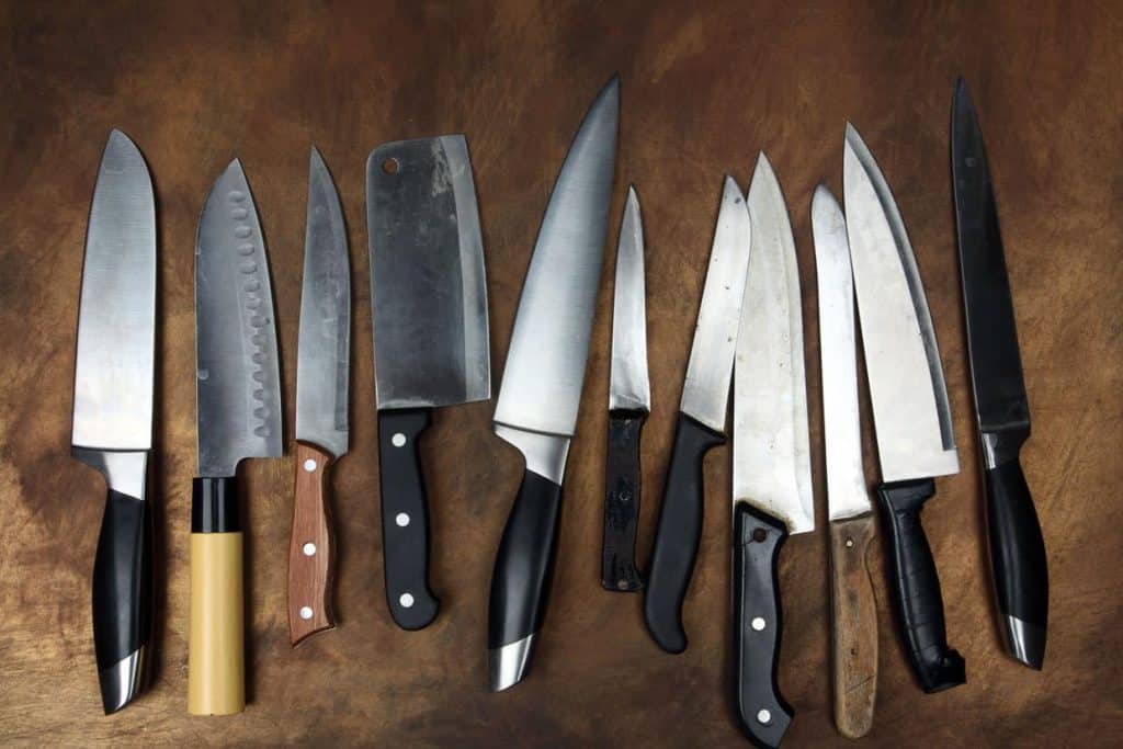 A group of knives arranged on a wooden surface.