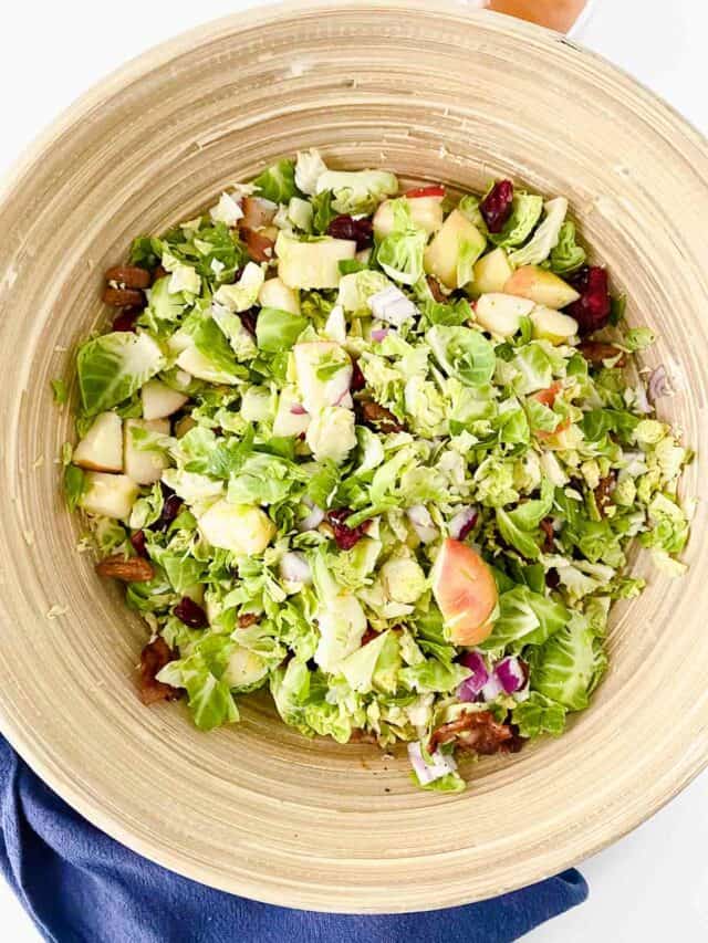 A bowl of brussels sprout salad with apples and cranberries.