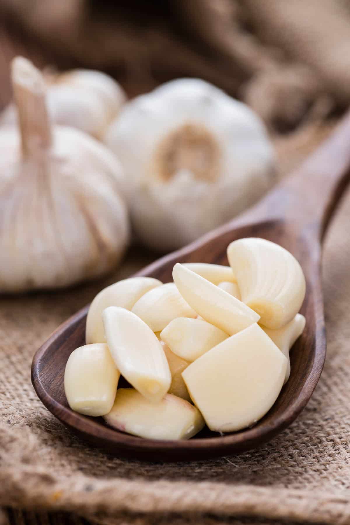 A wooden spoon with peeled garlic cloves.