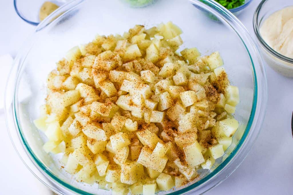 Diced apples seasoned with cinnamon in a glass bowl, ready for a recipe.