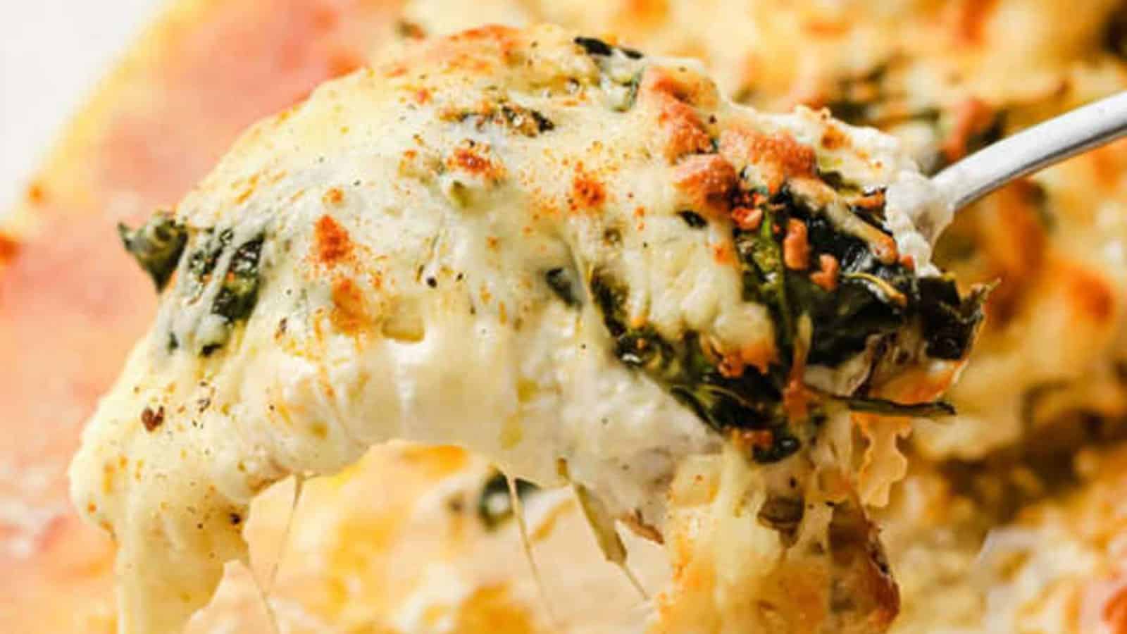 A serving spoon serving of creamy spinach chicken bake.