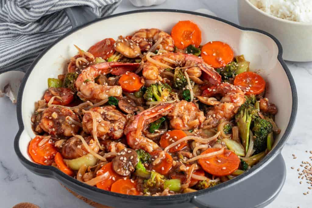 A dish with shrimp, vegetables, and noodles in a skillet.
