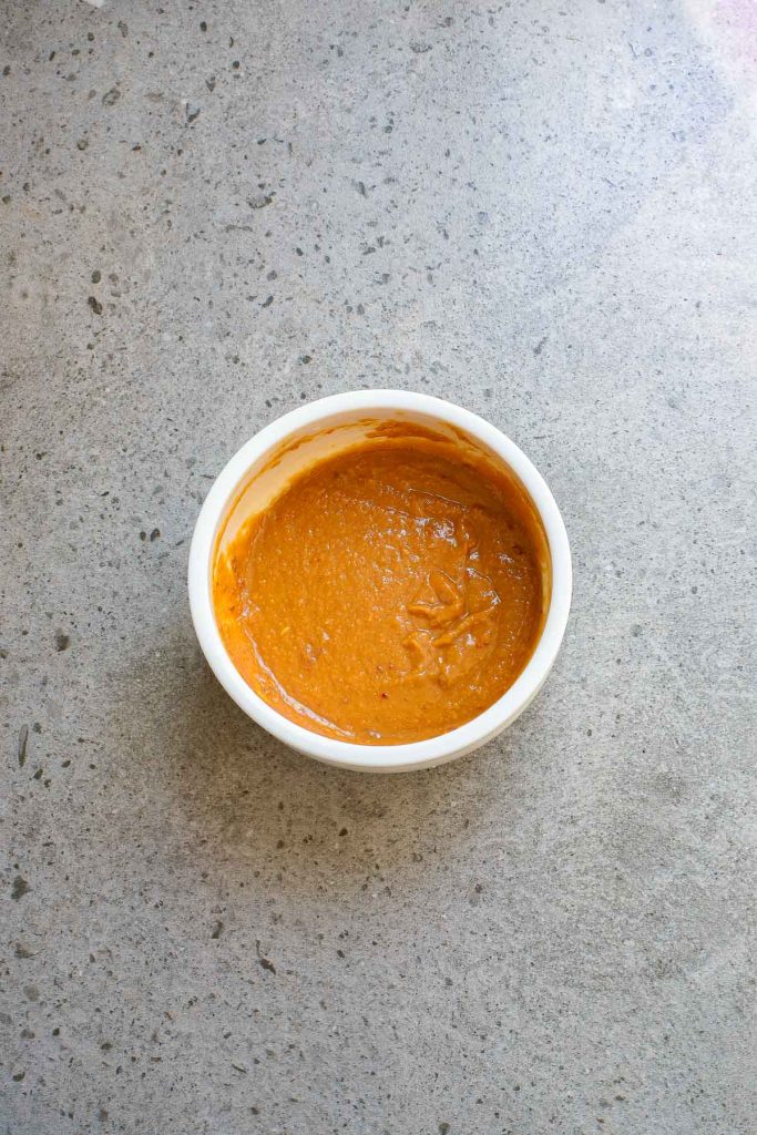 A white bowl filled with smooth brown sauce on a speckled gray countertop.