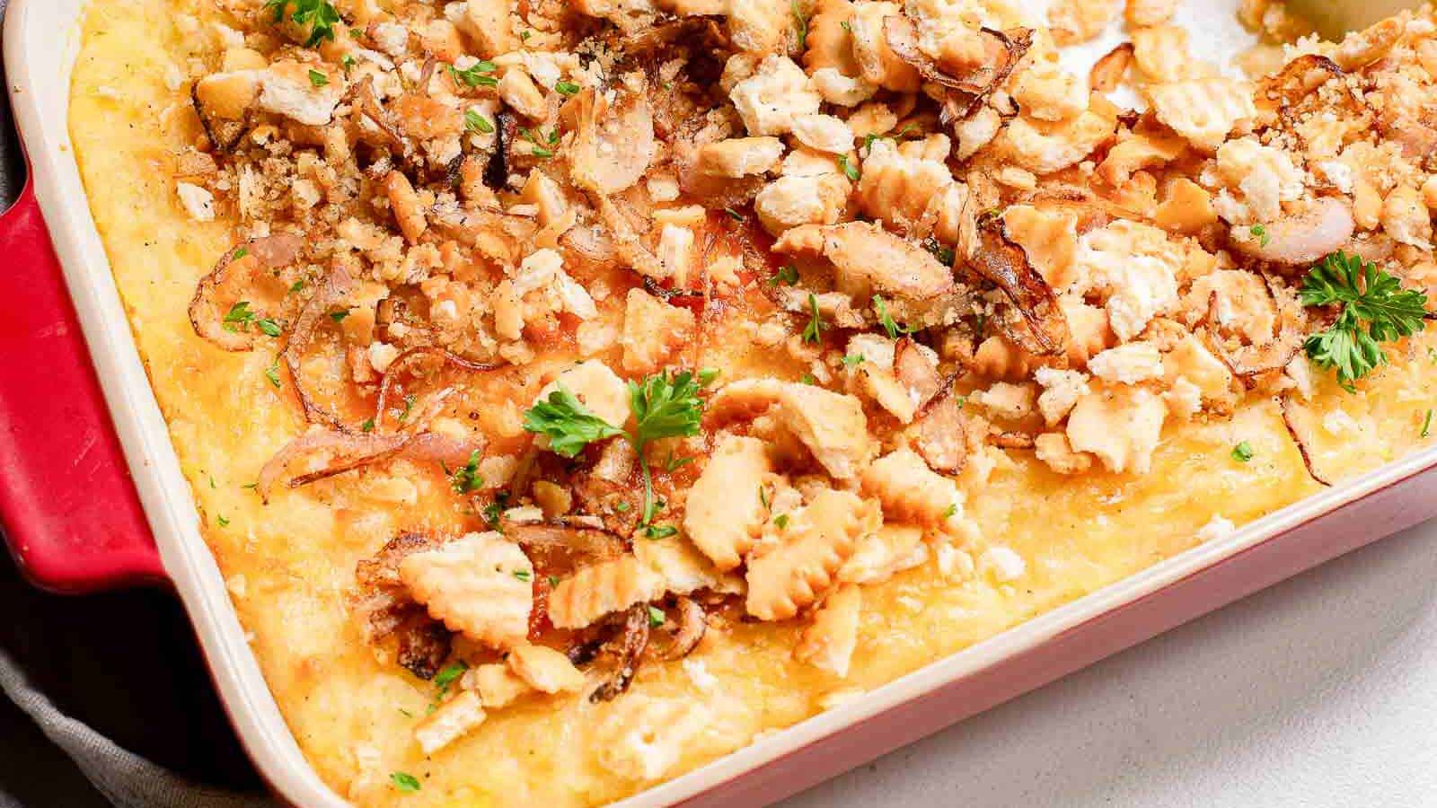 Masshed potato casserole in a baking dish with a cracker crumb topping.