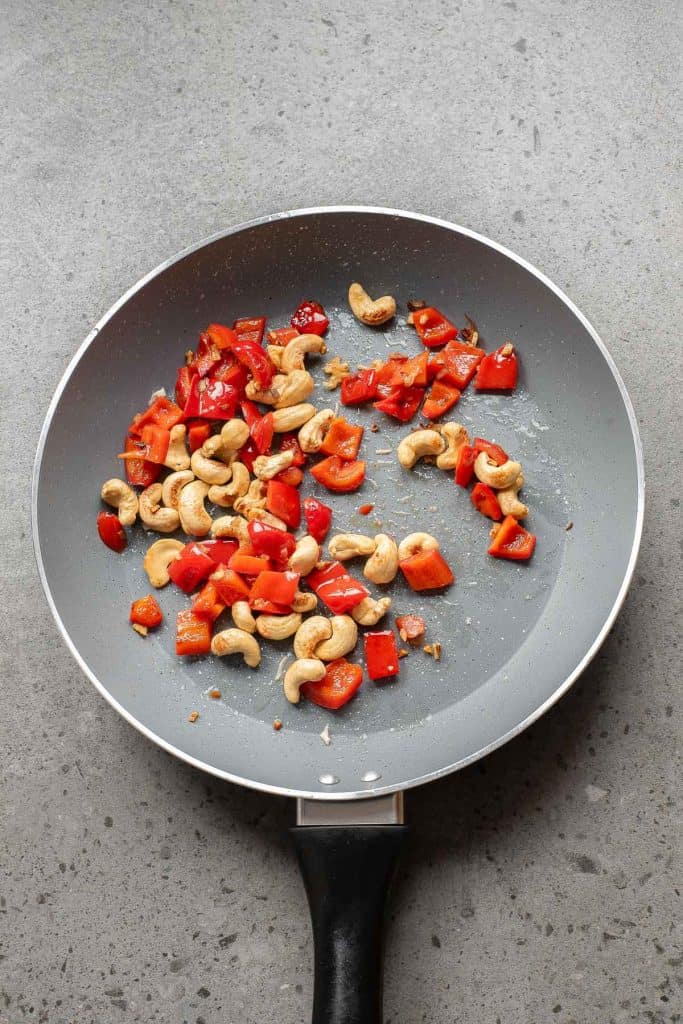 A pan with cashews and red peppers.