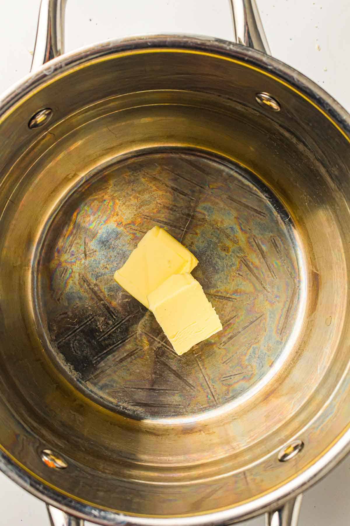 Two slices of butter in the center of a stainless steel pot.