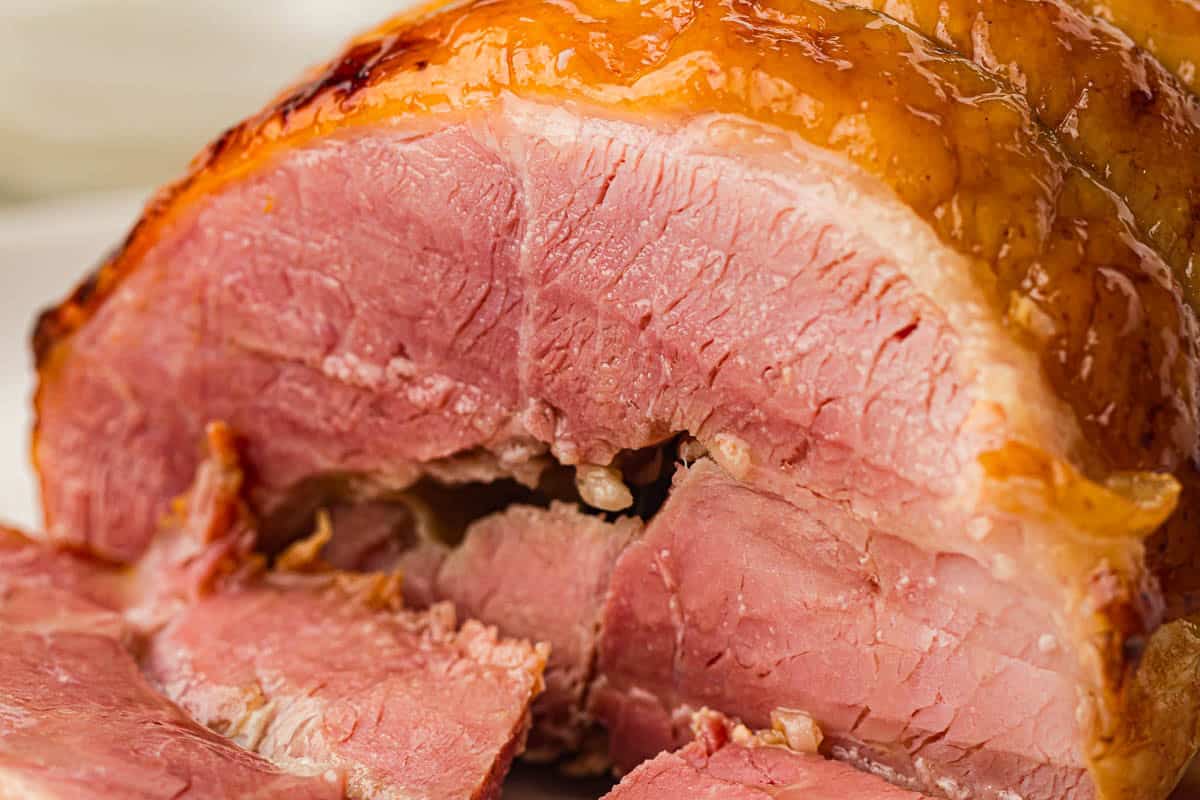 Close-up of a sliced cooked ham showing its pink interior and glazed, browned outer crust.