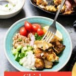 A hand uses a fork to pick up chicken from a bowl with tomatoes, cucumber, onions, grain, sauce, and lemon; a skillet and sauce are in the background. Text reads “Chicken Shawarma Bowl.”.
